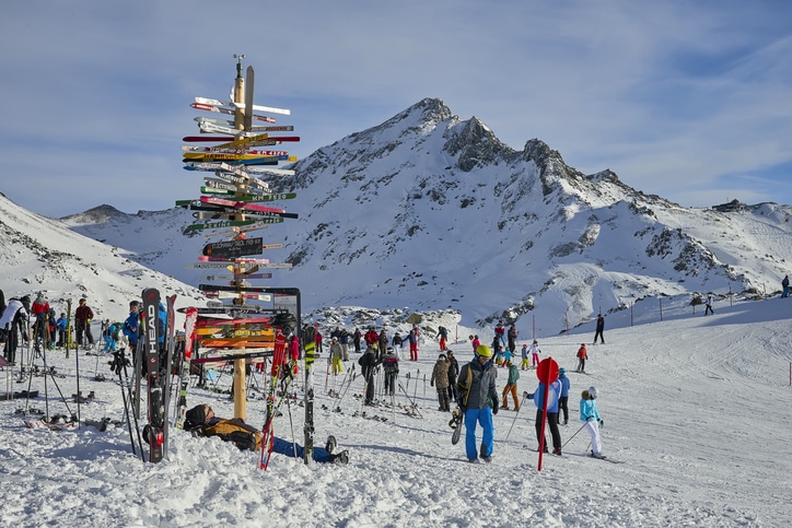 גולשים עומדים סביב שלט ייחודי המורה על מסלולי הסקי השונים שבאזור הכפר אישגל