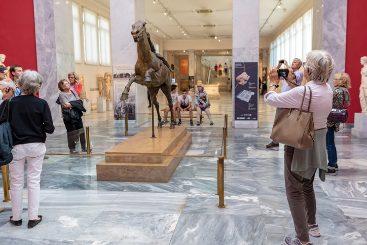מבקרים מתרשמים מהמיצגים והתערוכות בתוך המוזיאון הלאומי לארכיאולוגיה באתונה