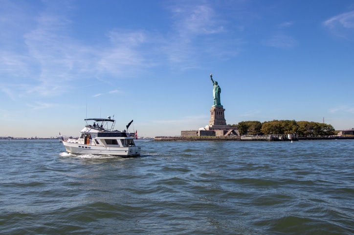 אי החירות עליו ניצב פסל החירות וסירה הלוקחת תיירים לסיור שייט