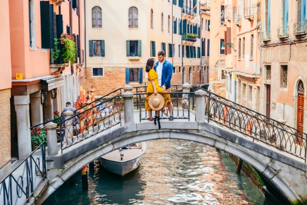 זוג עומד במרכז גשר מעל אחת מהתעלות בונציה
