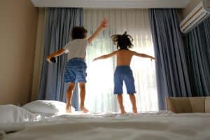 ילדים קופצים על המיטה בחדר במלון
